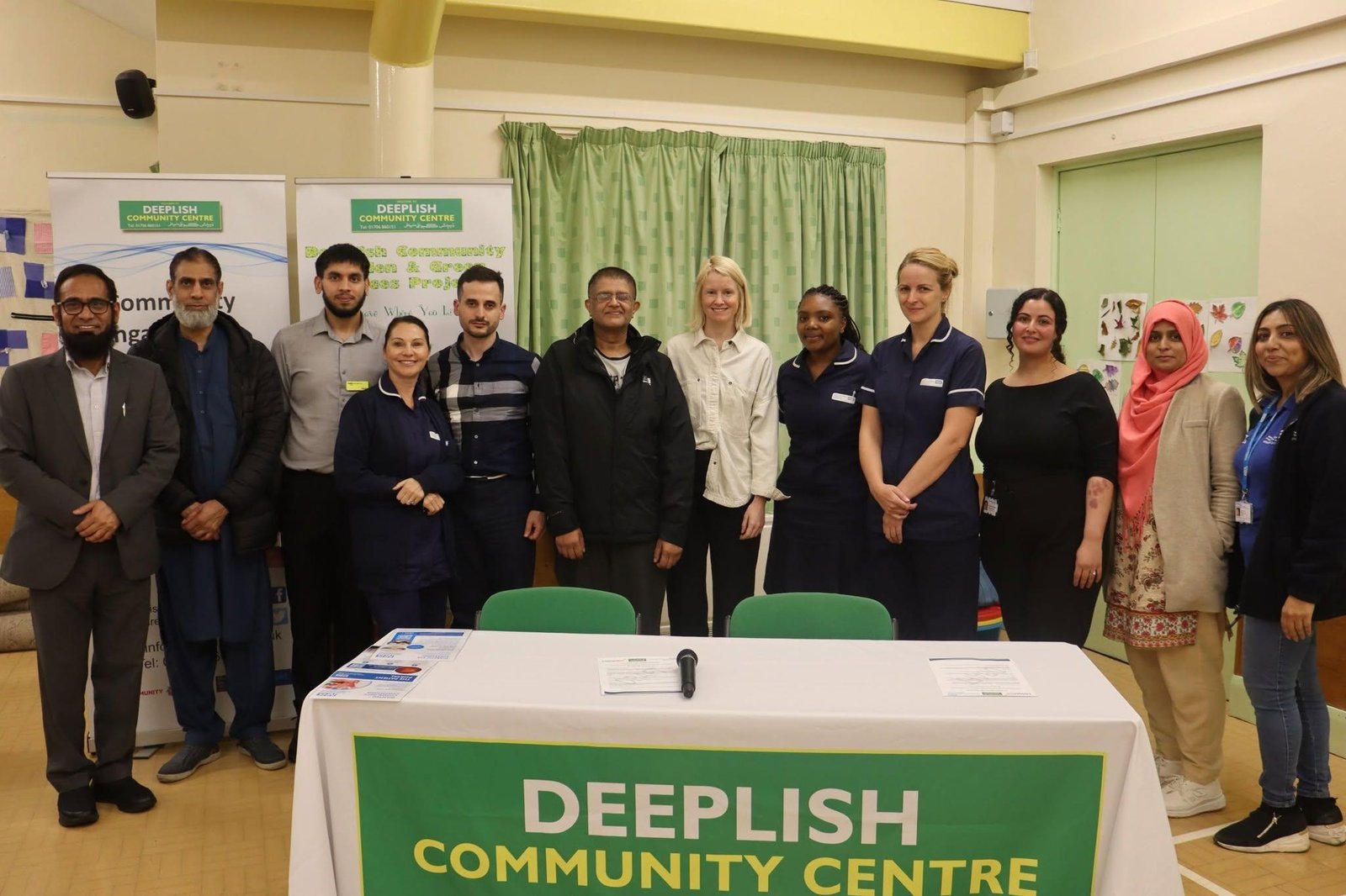 Group photograph at an NHS community seminar with Deeplish Community Centre branding